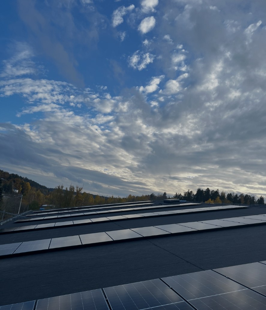 Parallella rader av solpaneler på ishallens tak i Valdemarsvik under en molig himmel