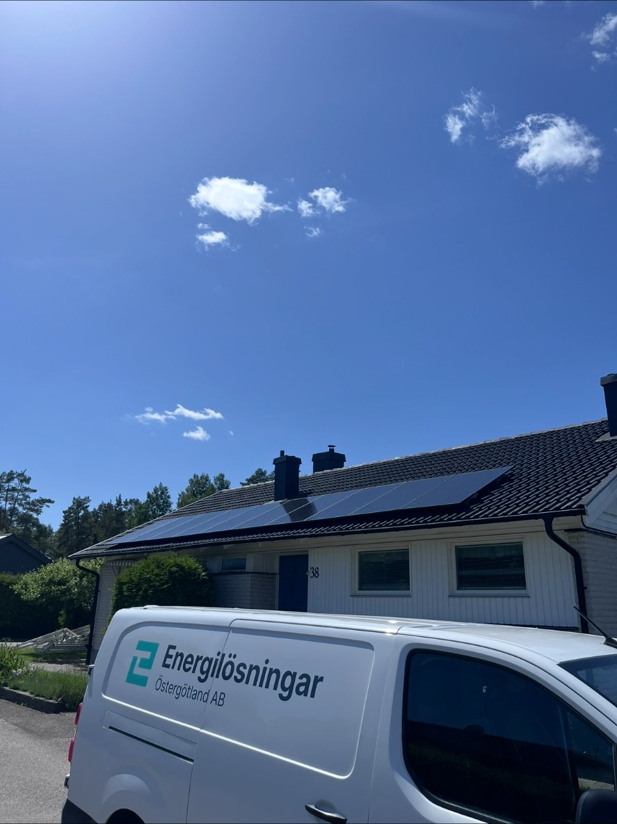 Solcellspaneler i en rad på villans mörka tegeltak i Linghem, med Energilösningar Östergötlands tjänstebil framför huset