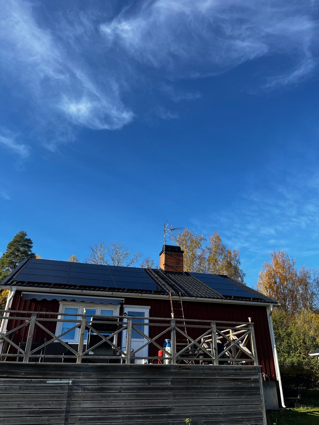 Svarta solcellspaneler i två sektioner på det mörka tegeltaket till en rödfasad villa i Motala